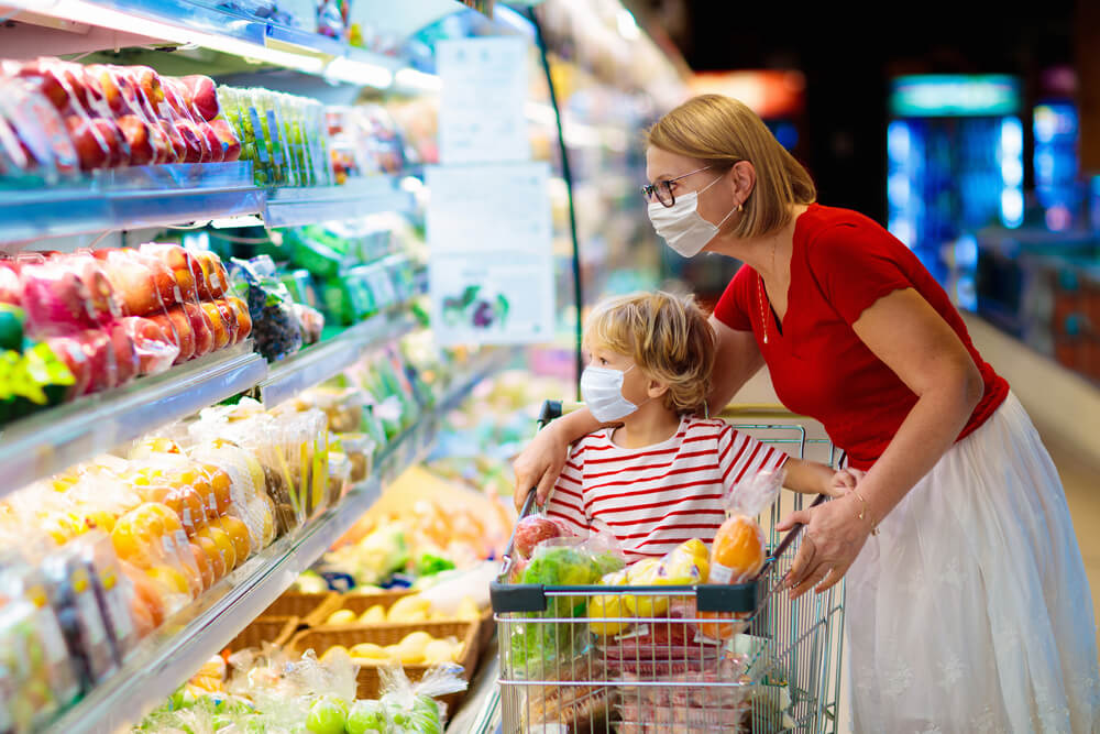 Mulher com criança em supermercado, olhando uma estufa de produtos orgânicos.